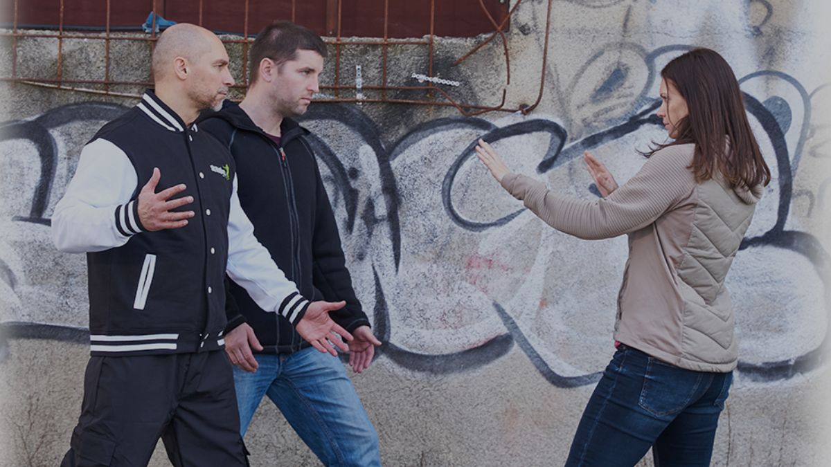 Selbstverteidigung: Eine Frau hält Distanz zu mehreren Angreifern in einer Bedrohungssituation
